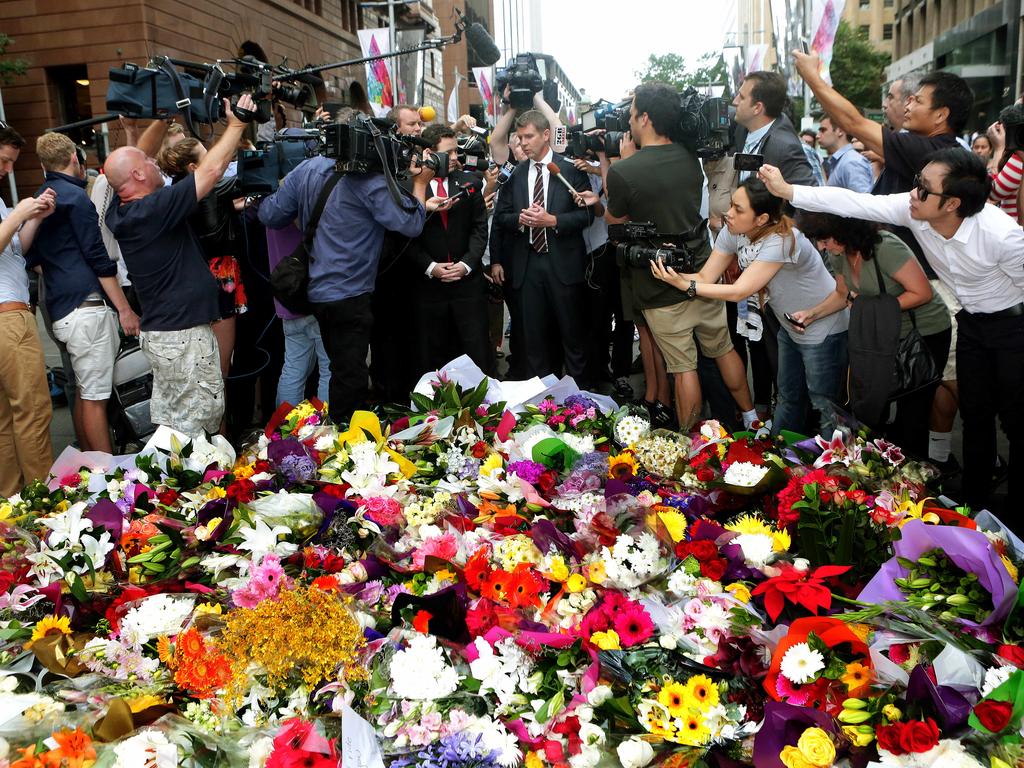 NSW Premier Mike Baird visits a rapidly growing flower memorial in Martin Place.