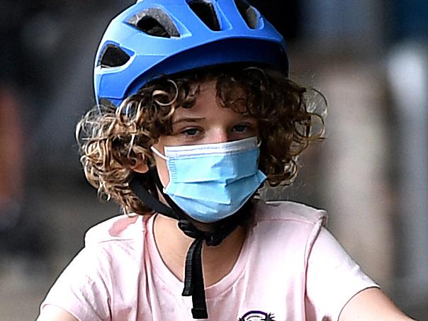 BRISBANE, AUSTRALIA - NewsWire Photos - JANUARY 10, 2021.A child wears a face mask while riding a bike at Southbank during the second day of COVID-19 lockdown in Brisbane. Greater Brisbane is under a 3-day lockdown orders after a quarantine hotel worker tested positive to the UK strain of the COVID-19 corona virus. Picture: NCA NewsWire / Dan Peled