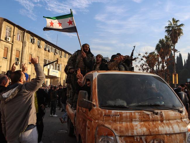 Syrian rebel fighters celebrate near the Clock Tower in Homs on December 8, 2024, after rebel forces entered Syria's third city overnight. Islamist-led rebels declared that they have taken Damascus. Picture: AFP