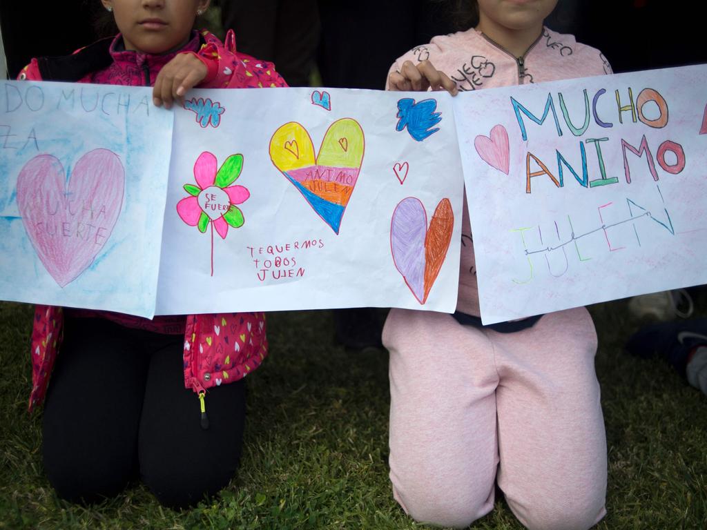 Two girls hold drawings bearing hearts and messages of support for the little boy. Picture: AFP