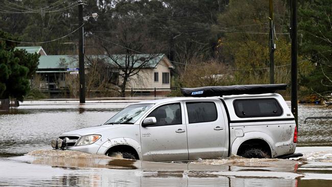 A resident drives through floodwaters along the overflowing Nepean River in western Sydney on Tuesday. Picture: AFP