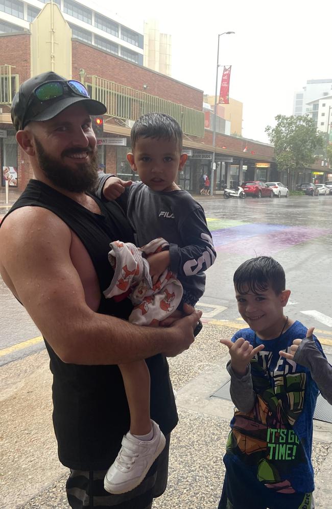 Chris Gatt and his sons Hunter and Ryland take shelter from the monsoonal rain on New Year's Eve. Picture: Riley Walter