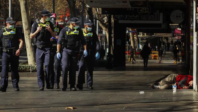 Victoria police walk past a homeless man along Swanston Street in Melbourne‘s CBD. Picture: NCA NewsWire / Daniel Pockett