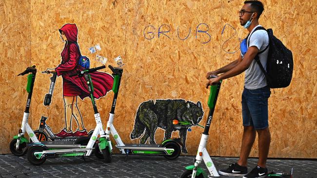 A man rides an electric scooter past a mural by Italian street artist Mauro Pallotta, aka Mau Pal, in Rome. Picture: AFP