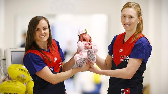 estern Bulldogs and Melbuorne women's team play this week. The Melbourne captain, Daisy Pearce (left) , is a midwife at Box Hill hospital. Drafted to Melbourne in the mini draft a few weeks ago was obstetrician Tirana Erns (right) They pass baby Ruby to each other Picture:Wayne Ludbey