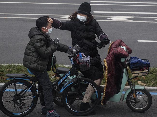 A woman checking her son’s forehead in Wuhan, China. Picture: Getty