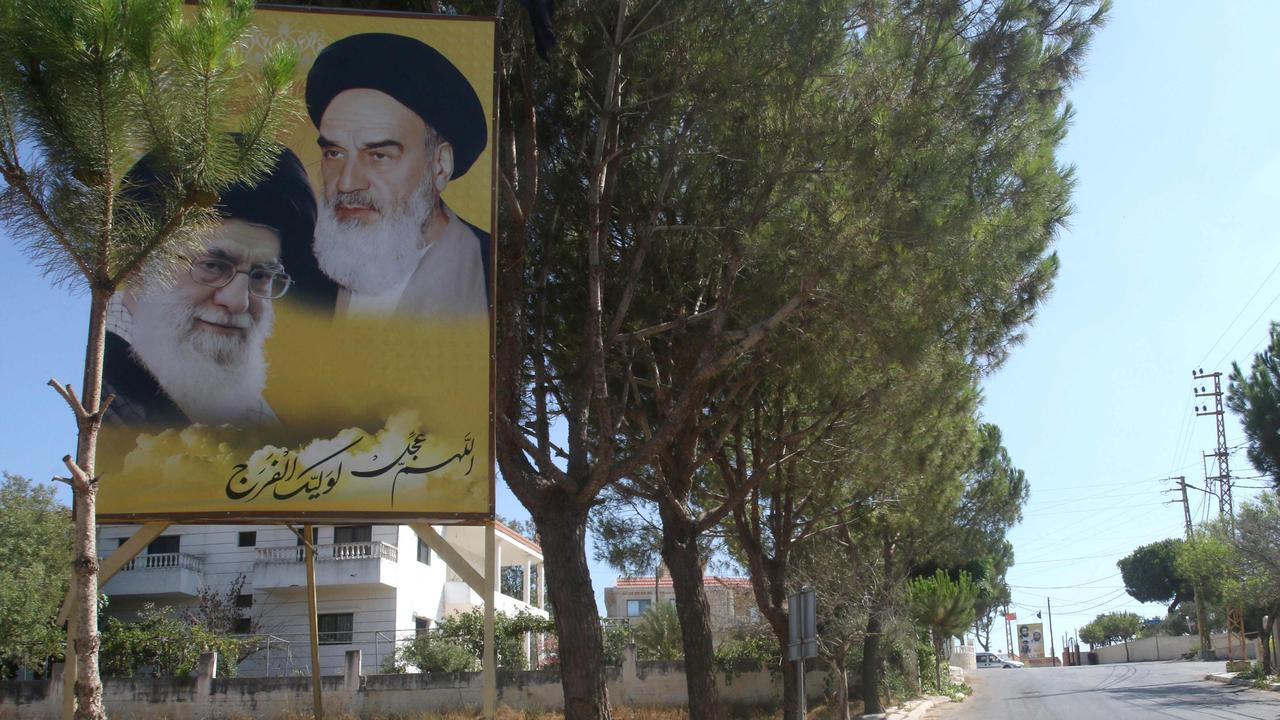 A poster depicting Iran’s Supreme Leader Ayatollah Ali Khamenei, left. Picture: Mahmoud Zayyat/AFP