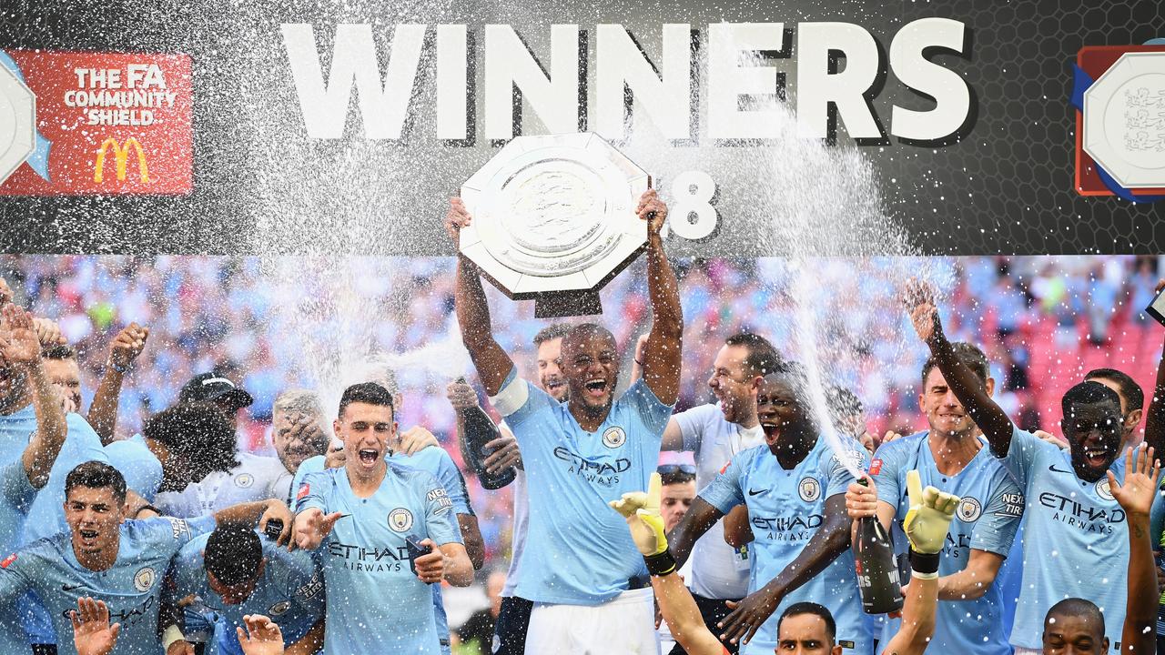 Manchester City players celebrate as Vincent Kompany of Manchester City lifts the trophy.