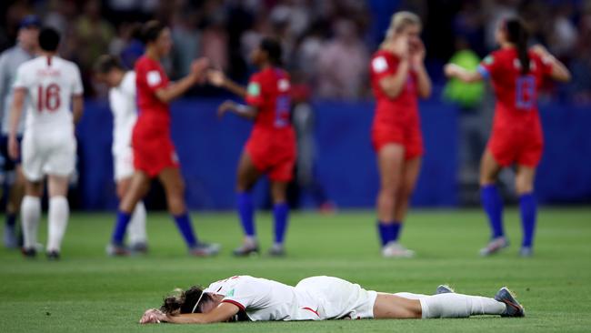 England player Lucy Bronze buries her face in the turf as USA players celebrate behind her. Picture: Getty Images
