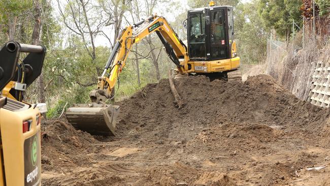 Excavators dig as police search a storm water drain running under Cobalt Road in Carole Park. Picture: Jono Searle