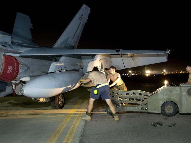 Air Task Group Strike Element Armament Technicians load ordnance on to an F/A-18A Hornet on the flight line of Australia's main air operating base in the Middle East region.