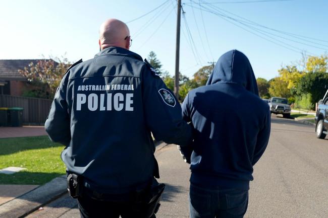 An Australian Federal Police officer arrests a suspect allegedly involved with an encrypted messaging app used by criminals worldwide