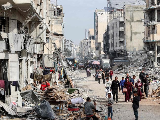 TOPSHOT - People walk past the rubble of collapsed and damaged buildings along a street in Gaza City on December 11, 2024 amid the ongoing war in the Palestinian territory between Israel and Hamas. (Photo by Omar AL-QATTAA / AFP)