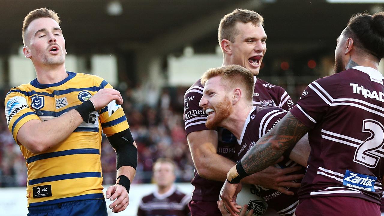 Bradley Parker of the Sea Eagles celebrates with teammates after scoring a try as Clint Gutherson of the Eels commiserates.