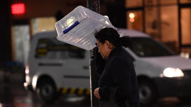 A woman tries to shelter from the rain in the CBD on Thursday evening. Picture: Tricia Watkinson