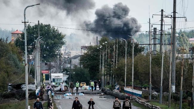TOPSHOT - A woman (3rd R), evacuating with belongings, protects her ears after an explosion on a bridge over the Oskil River as black smoke rises in the frontline city of Kupiansk, Kharkiv region, on September 24, 2022, amid the Russian invasion of Ukraine. - In the northeastern town of Kupiansk, which was recaptured by Ukrainian forces, clashes continued with the Russian army entrenched on the eastern side of the Oskil River. (Photo by Yasuyoshi CHIBA / AFP)