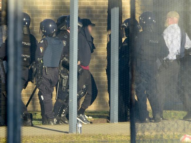 Riot police lead a detainee away in handcuffs during a riot at the Frank Baxter Juvenile Justice Centre, Kariong on Monday. Picture: AAP Image/Bianca De Marchi