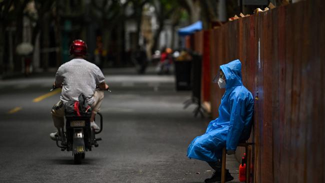 A worker sits next to a fence erected to close a residential area under Covid-19 lockdown in the Huangpu district of Shanghai in June. Picture: AFP