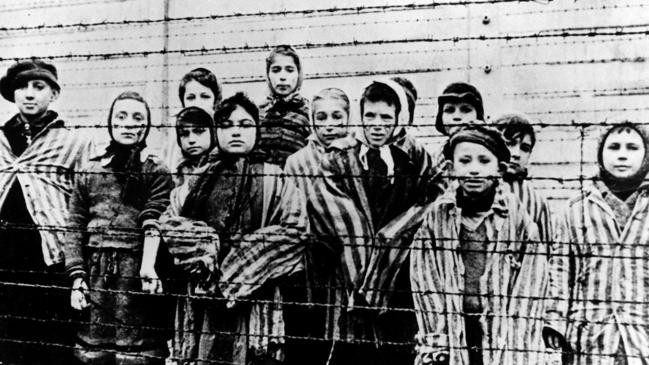 A group of children wearing concentration camp uniforms behind barbed wire fencing in the Oswiecim (Auschwitz) Nazi concentration camp.