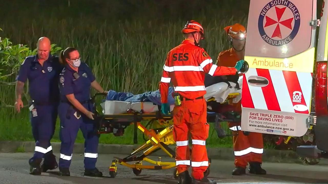 An injured man is loaded into an ambulance after a crash that happened in an exit lane from the Pacific Highway at Moonee Beach on March 9, 2022.