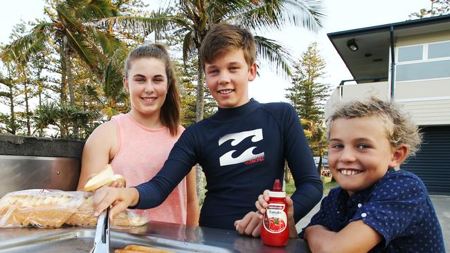 Georgia, Sam and Will Brown use a council barbeque at Burleigh Heads to cook some chicken sausages. Picture: Brendan Radke.