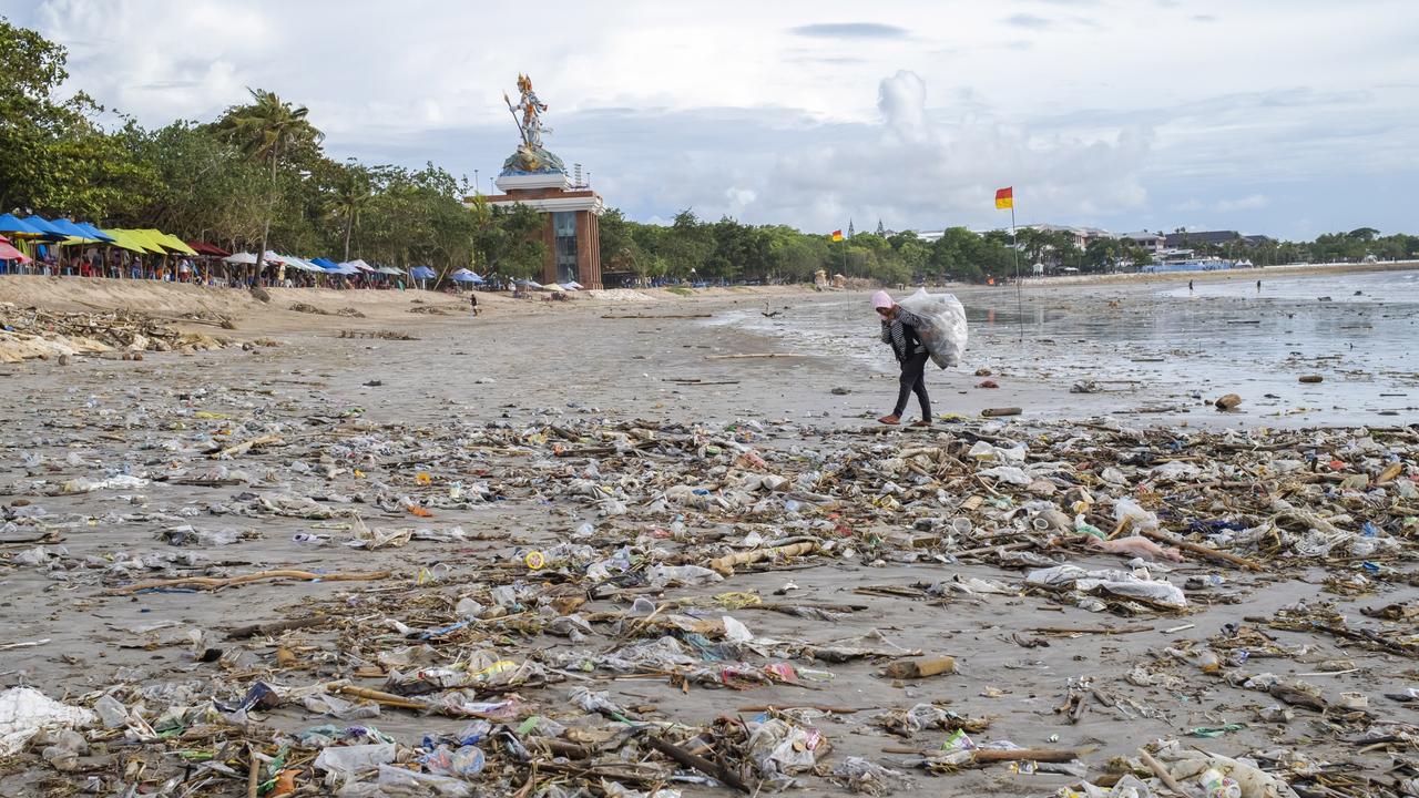 Here she is snapped with a huge garbage bag over her shoulder as she continues to clear the washed up waste. Picture: Made Nagi/EPA/AAP