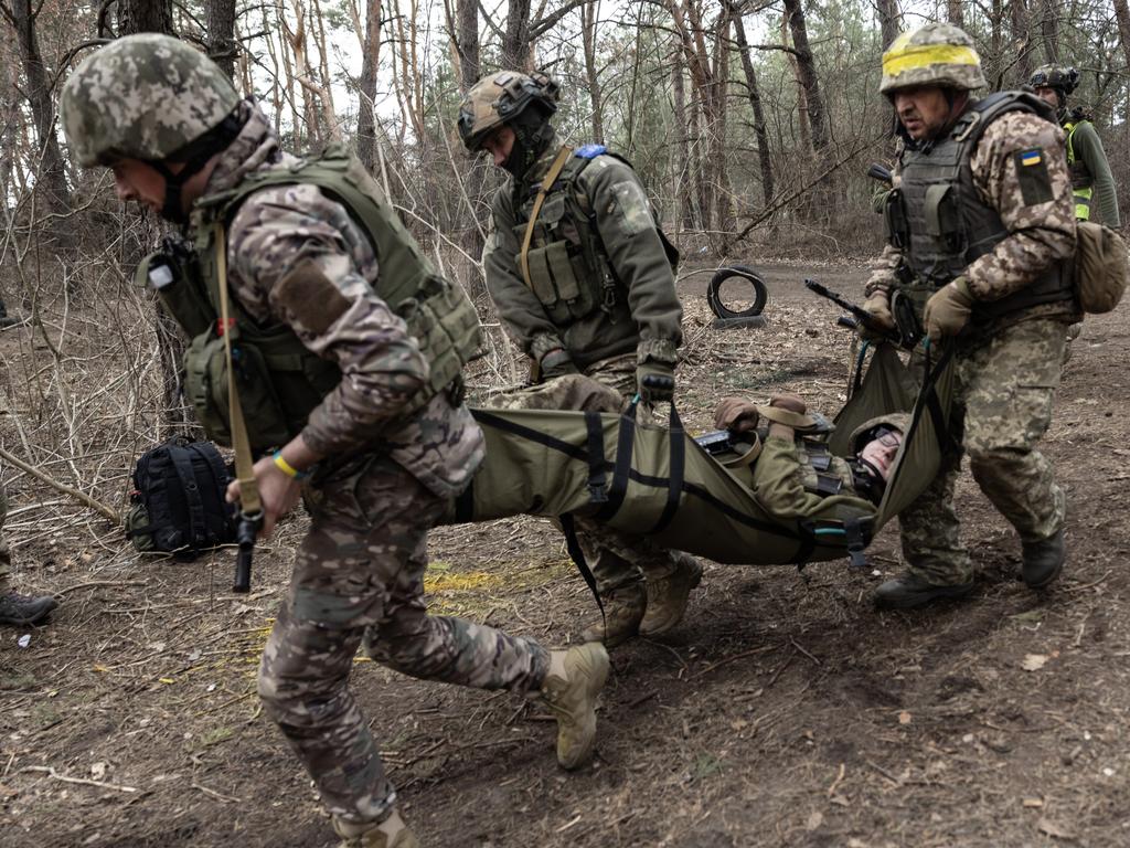 Newly recruited Ukrainian soldiers with the 33rd Separate Mechanised Brigade practice carrying a wounded soldier during military training. Picture: Getty Images