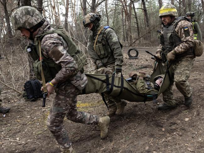 Newly recruited Ukrainian soldiers with the 33rd Separate Mechanized Brigade practice carrying a wounded soldier during military training. Picture: Getty Images