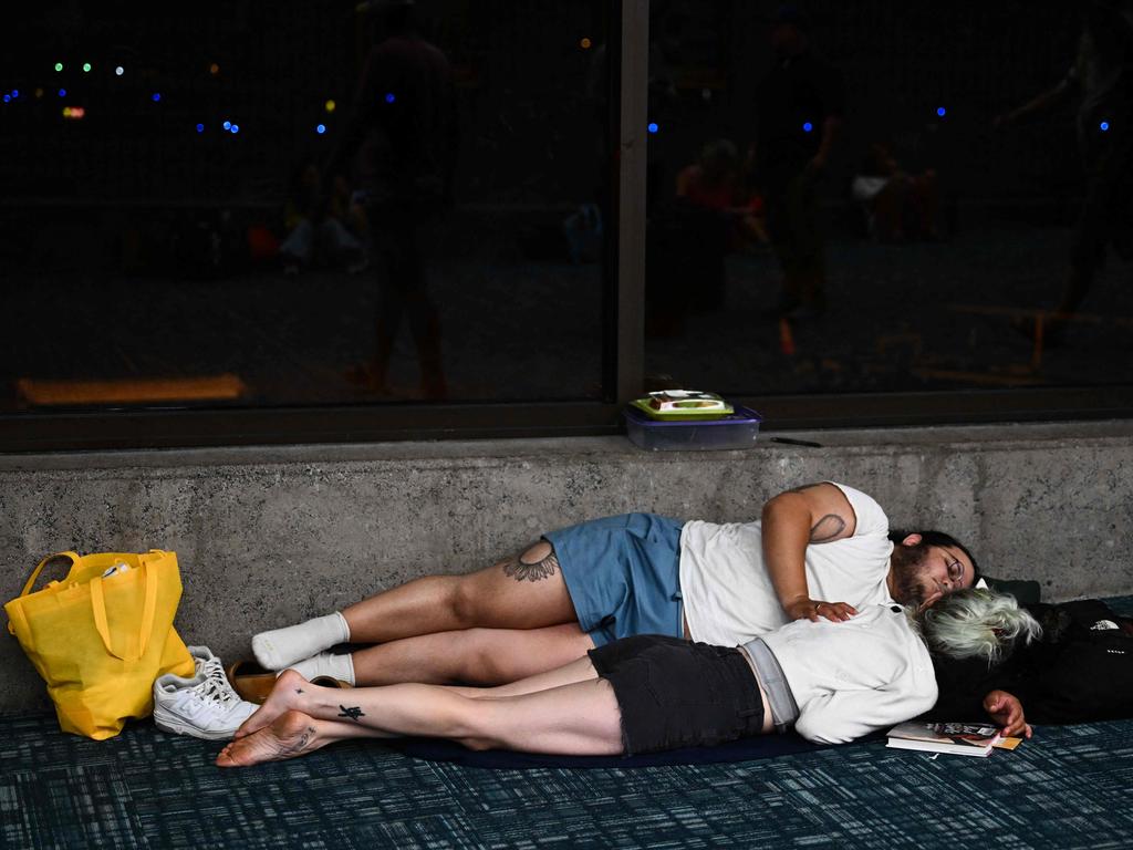 Tourists sleep on the floor of the airport terminal while waiting for delayed and cancelled flights out of Hawaii. Picture: AFP