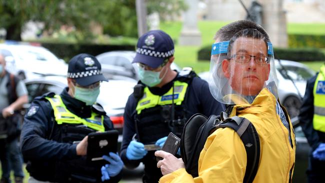 An anti-lockdown protester wearing a Daniel Andrews mask is confronted by police near the Shrine of Remembrance in Melbourne. Picture: Andrew Henshaw