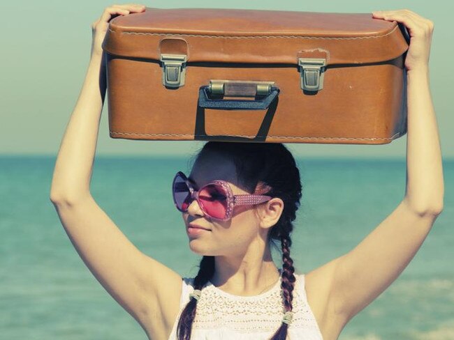 woman with suitcase on the beach