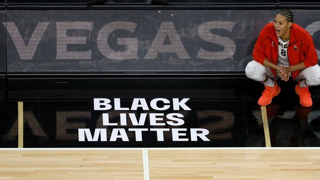 Liz Cambage squats near a BLM logo in Las Vegas this year during a WNBA game. Picture: Getty