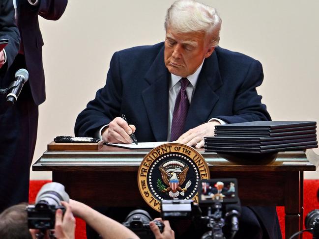 US President Donald Trump signs executive orders during the inaugural parade inside Capital One Arena, in Washington, DC, on January 20, 2025. (Photo by ANGELA WEISS / AFP)