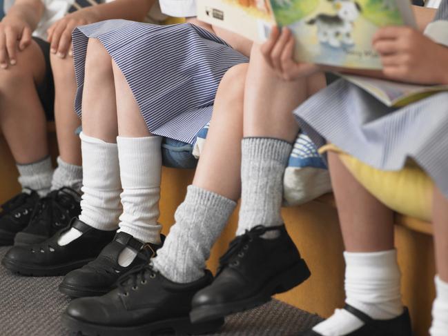 Low section of elementary students sitting in row in classroom