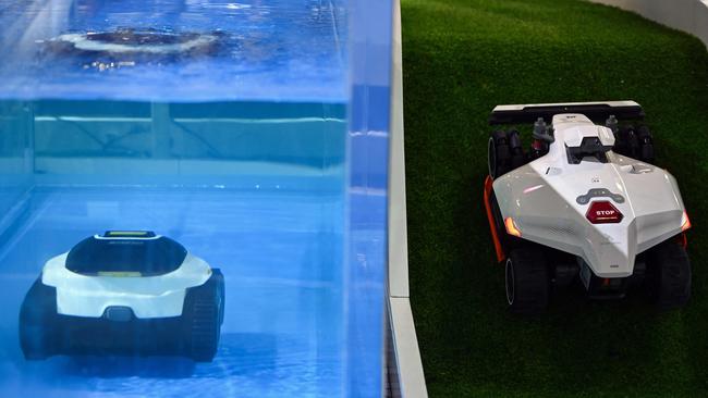 The MAMMOTION Luba 2 AWD lawnmower (R) drives past an underwater pool cleaner (L) during the Consumer Electronics Show. Picture: AFP