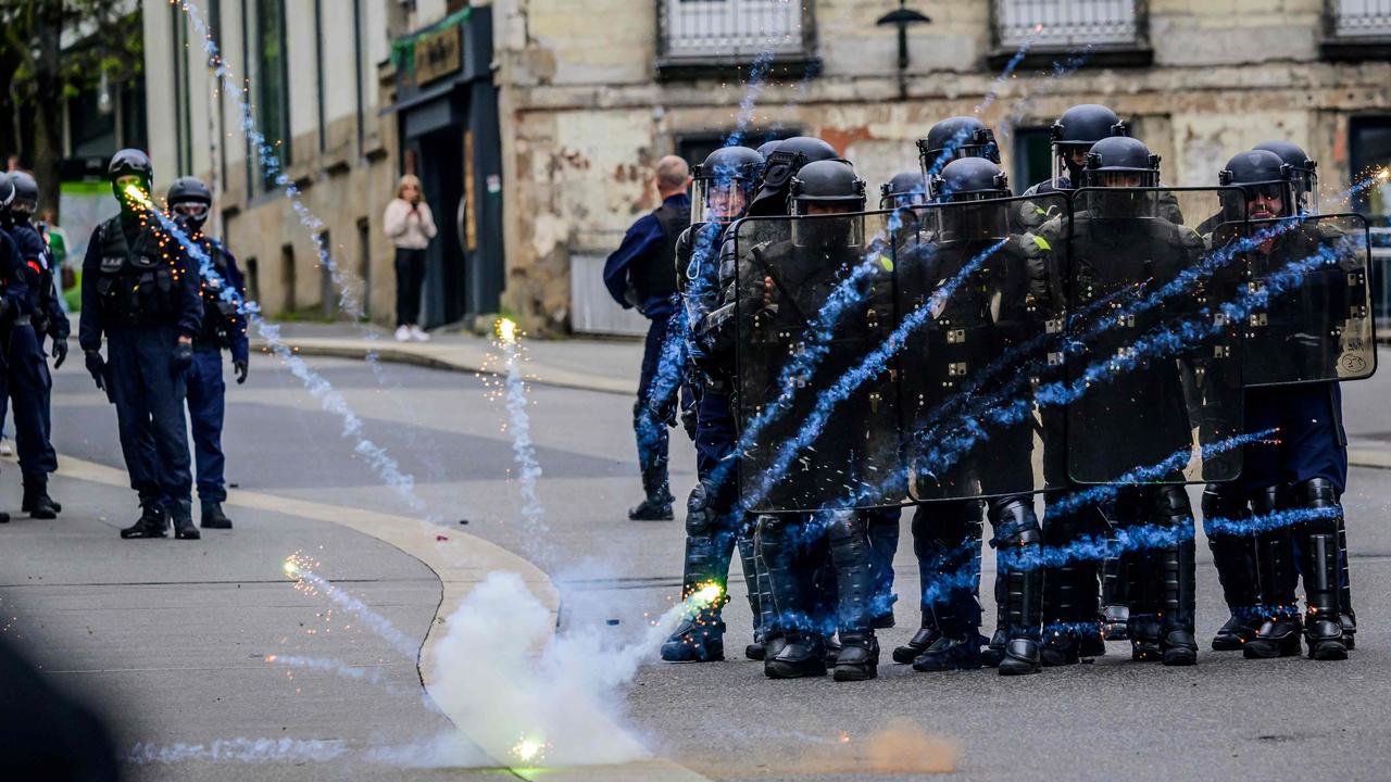 Police in riot gear stand in formation as protesters throw fireworks during a May Day rally in Nantes, France. Picture: Loic Venance/AFP