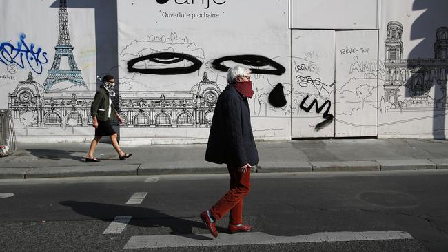 People wearing hand made protective masks walk the empty streets of Paris. Picture: AP