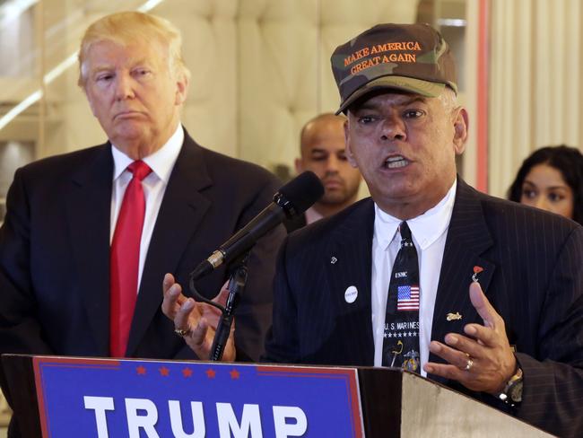 Donald Trump listens as Al Baldasaro, a New Hampshire state representative, speaks during a news conference.