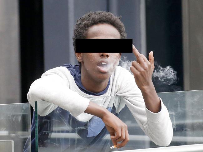 A young teen makes a rude gestures as he smokes outside the Blacktown shopping centre.