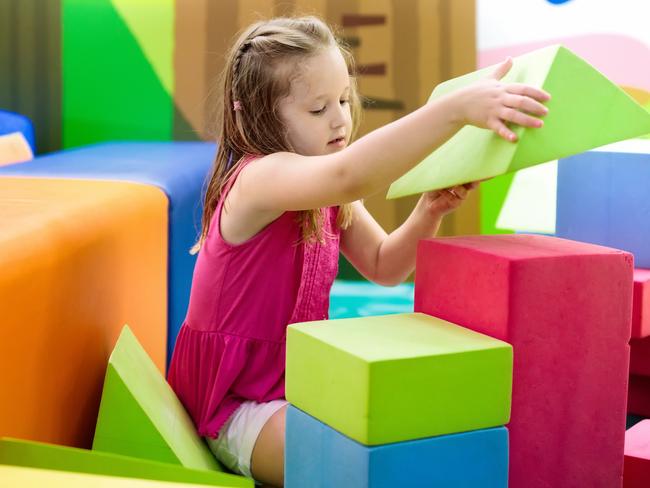 Child playing with colorful construction toy blocks. Educational toys for young kids. Kindergarten or preschool play room. Toddler kid at day care playground. Girl building house with block at daycare