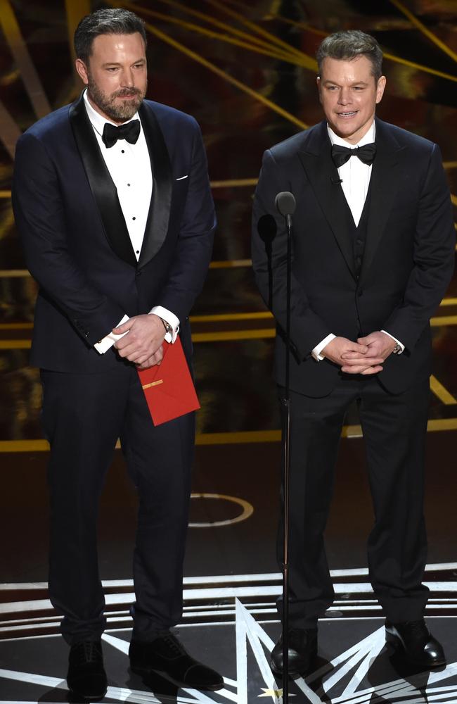 Affleck and Damon TRYING to present the Academy Award for Best Original Screenplay. Picture: AP