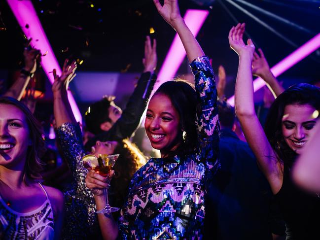 Cocktails. Friends. Happy afro american young woman dancing with her friends while on a night club party with confetti and holding a drink on her hand Picture: istock