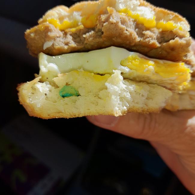 The sausage and egg McMuffin with part of the green plastic glove in it.