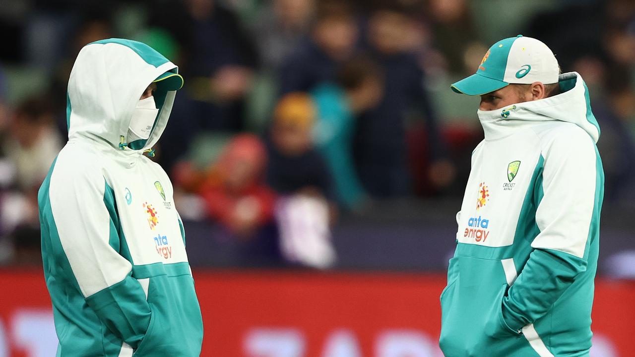 Aaron Finch covers his mouth while chatting to Matthew Wade (left).