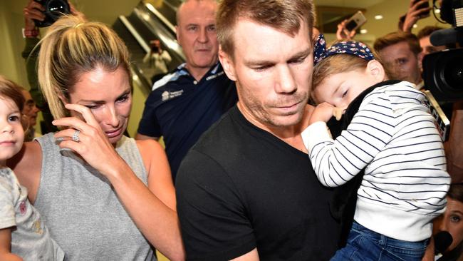 Australian cricketer David Warner (C), his wife Candice and their daughters leave the airport after arriving back in Sydney on March 29, 2018. Picture: AFP / Peter Parks.