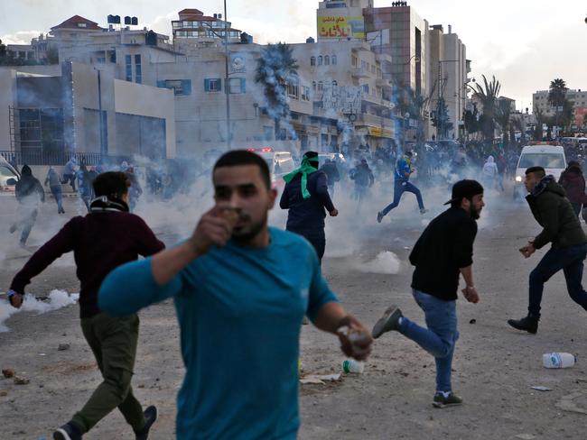 Palestinian protesters run for cover from tear gas during clashes with Israeli troops near the Jewish settlement of Beit El, near the West Bank city of Ramallah. Picture: AFP