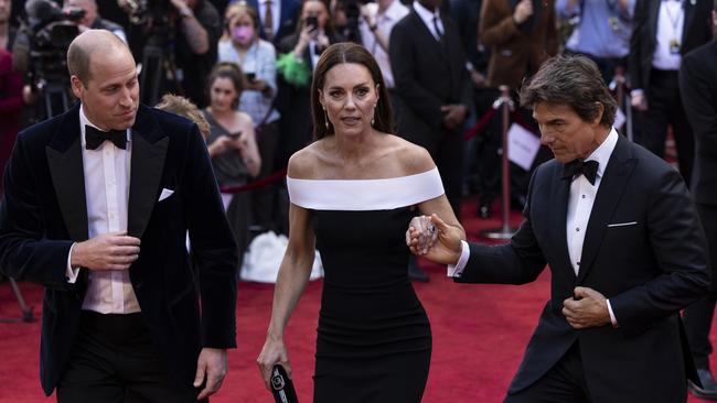 Tom Cruise takes Kate Middleton’s hand as they approach a set of stairs. Picture: Getty Images