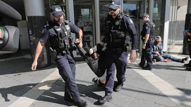 Police officers take Herbert to the paddy wagon.