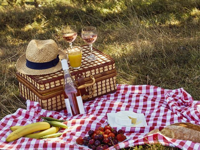 Wine bottle and glass on picnic basket along with hat