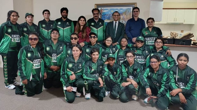 Zaffar Khan, in suit and tie, with the Pakistan Women Blind Cricket Team in a Facebook post on Sunday that praised him for making a $5000 donation, while his unpaid staff separately speak of their own desperate wait for cash.